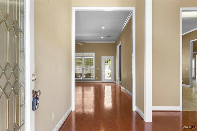 foyer featuring crown molding, wood finished floors, and baseboards