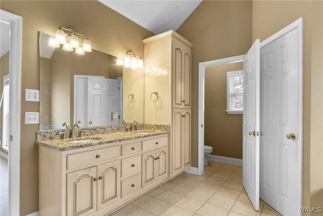 bathroom featuring tile patterned floors, vaulted ceiling, toilet, and a sink