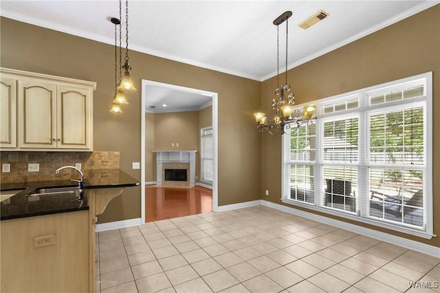 kitchen with visible vents, backsplash, crown molding, light tile patterned floors, and a sink