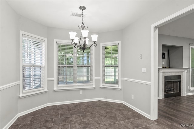 unfurnished dining area with a chandelier, dark hardwood / wood-style floors, and a fireplace