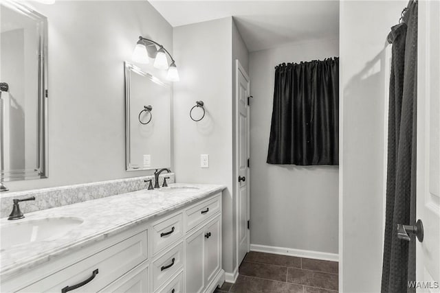 full bath featuring double vanity, tile patterned flooring, baseboards, and a sink