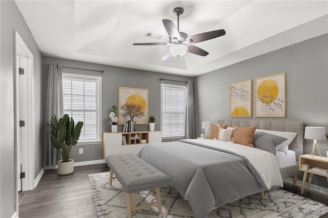 bedroom featuring a raised ceiling, ceiling fan, and dark hardwood / wood-style floors