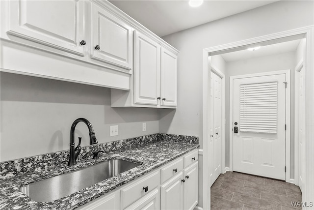 kitchen with white cabinetry, sink, and dark stone counters