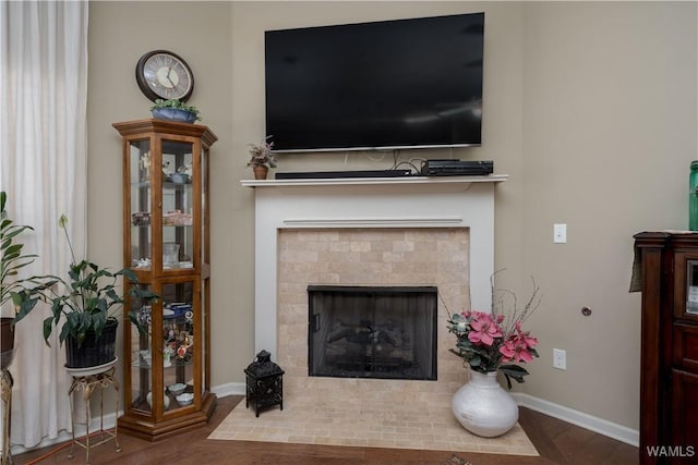 living room with baseboards, wood finished floors, and a tiled fireplace