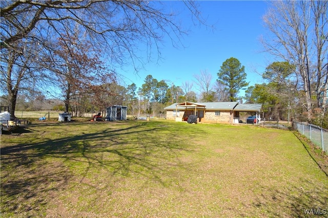 view of yard featuring fence, an outdoor structure, and a storage shed