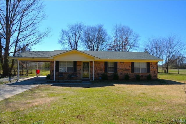 single story home featuring driveway, a front yard, an attached carport, and brick siding