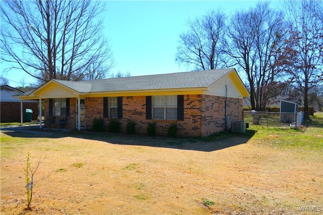 view of front of home featuring brick siding, fence, a front lawn, and central air condition unit