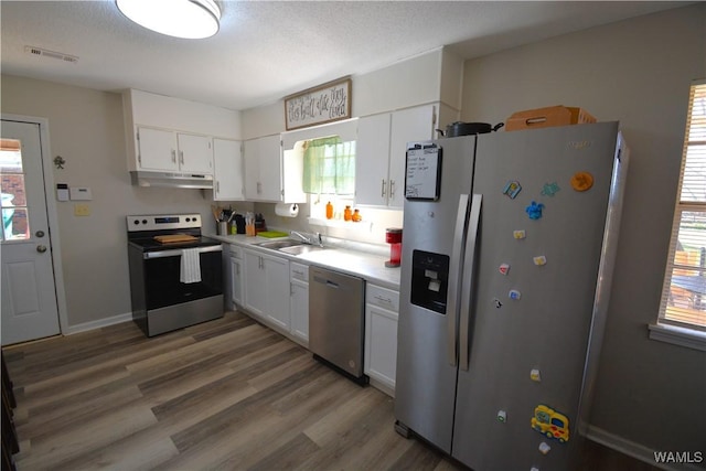 kitchen featuring under cabinet range hood, visible vents, white cabinets, light countertops, and appliances with stainless steel finishes