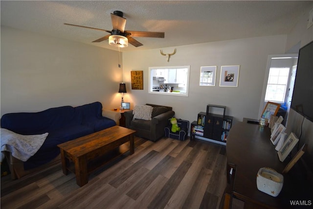 living area featuring dark wood-style floors, ceiling fan, and a textured ceiling