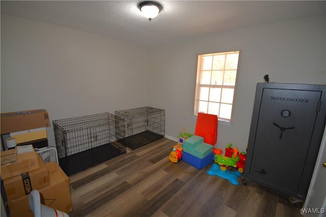 playroom featuring a textured ceiling, baseboards, and dark wood-style flooring