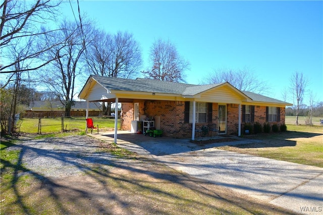 view of front of home featuring driveway, brick siding, a front yard, and fence