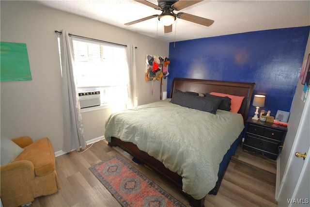 bedroom with a ceiling fan, baseboards, cooling unit, and wood finished floors