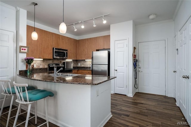 1901 5th Ave E Unit 2101, Tuscaloosa, AL 35401 - kitchen featuring tasteful backsplash, a peninsula, brown cabinetry, stainless steel appliances, and a sink