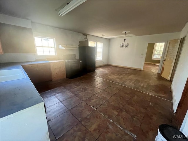 kitchen with baseboards, light countertops, a sink, and a chandelier