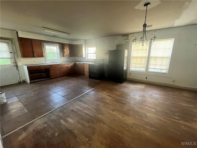 kitchen featuring light countertops, pendant lighting, a chandelier, dark wood finished floors, and baseboards