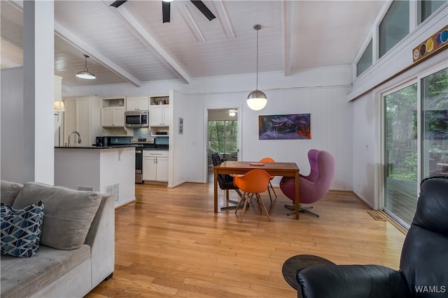 living room with light hardwood / wood-style floors, sink, ceiling fan, and beamed ceiling