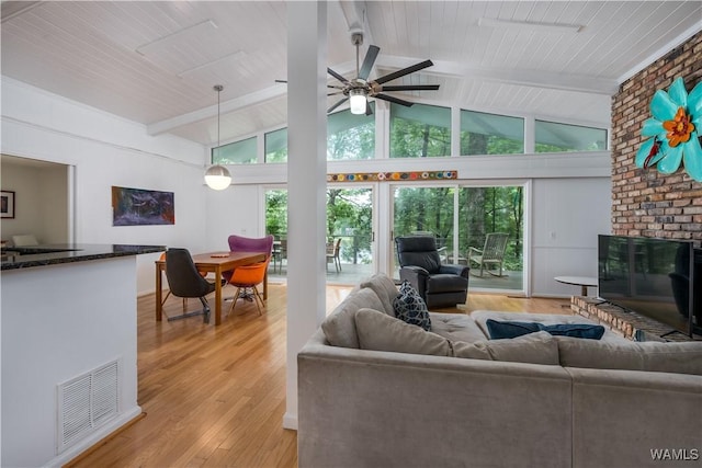 living room featuring light hardwood / wood-style floors, plenty of natural light, beamed ceiling, and a fireplace