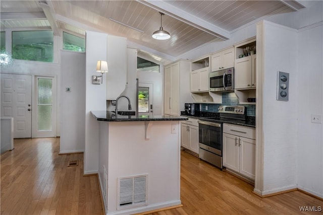 kitchen featuring light hardwood / wood-style flooring, hanging light fixtures, appliances with stainless steel finishes, white cabinetry, and vaulted ceiling with beams