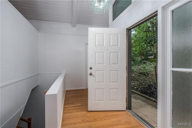 doorway with a chandelier, beam ceiling, and wood-type flooring