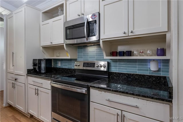 kitchen with white cabinets, light hardwood / wood-style flooring, dark stone countertops, and appliances with stainless steel finishes