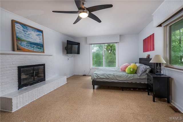 bedroom with a brick fireplace and ceiling fan