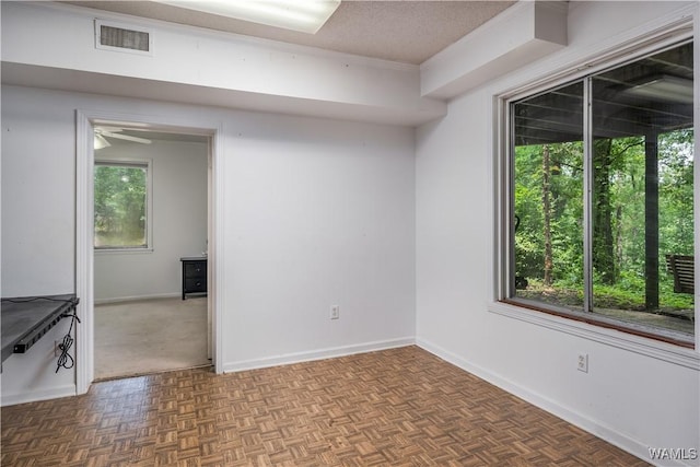 spare room featuring a textured ceiling and parquet flooring