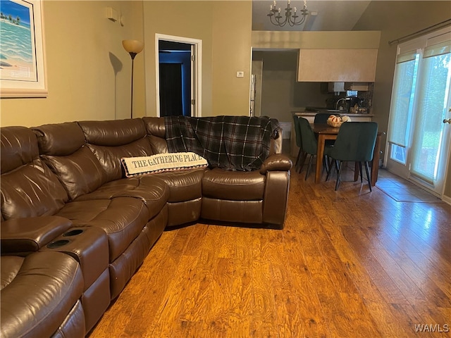 living room with wood-type flooring, lofted ceiling, and a notable chandelier