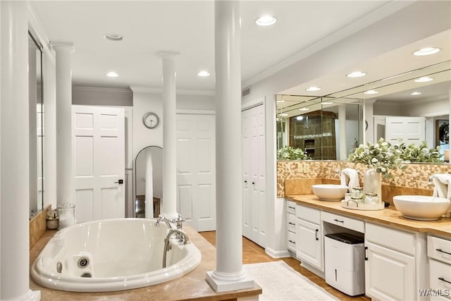 bathroom featuring vanity, a bath, crown molding, and decorative columns