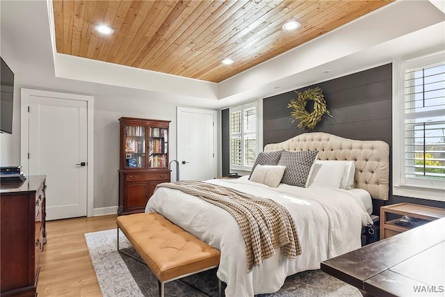 bedroom featuring multiple windows, wood ceiling, light hardwood / wood-style flooring, and a raised ceiling