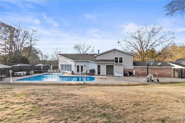 rear view of property featuring french doors, a fenced in pool, a patio area, and a lawn