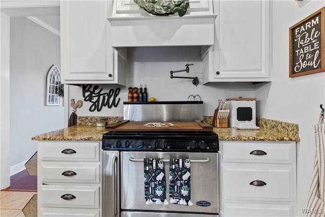 kitchen featuring ornamental molding, custom exhaust hood, dark stone countertops, white cabinets, and stainless steel range oven