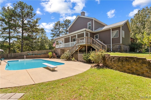 view of swimming pool with a yard, a patio, and a diving board