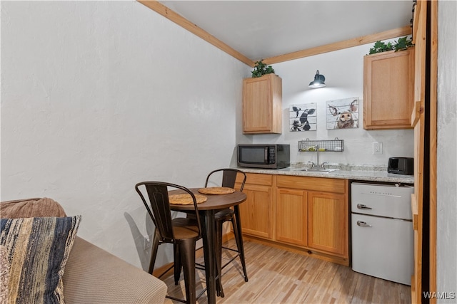 kitchen featuring light stone countertops, appliances with stainless steel finishes, light hardwood / wood-style floors, and sink