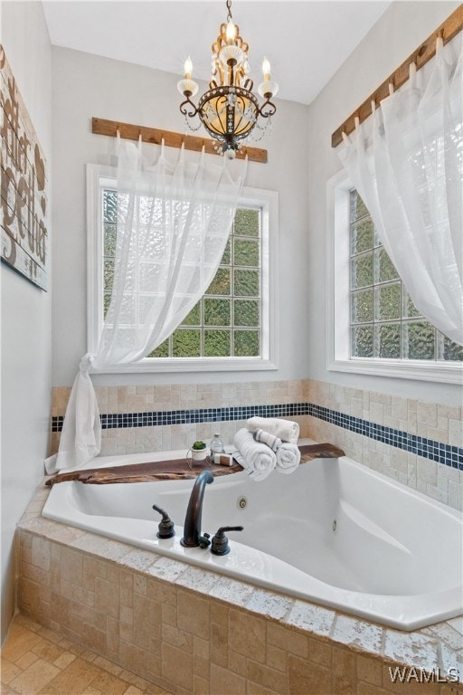 bathroom featuring tiled tub and an inviting chandelier