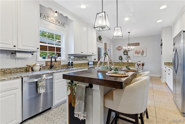 kitchen featuring white cabinets, wood counters, hanging light fixtures, and appliances with stainless steel finishes