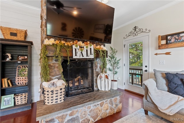 living room with a fireplace, crown molding, ceiling fan, and dark wood-type flooring