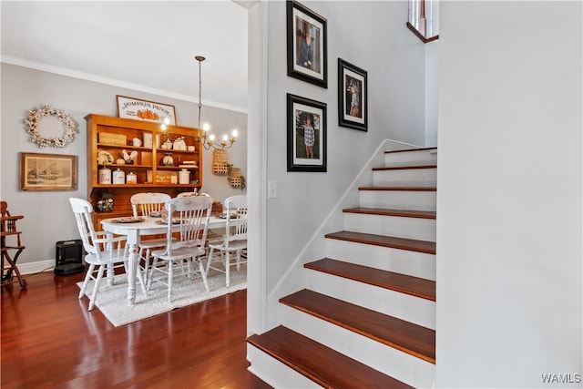 stairway with hardwood / wood-style floors, ornamental molding, and an inviting chandelier