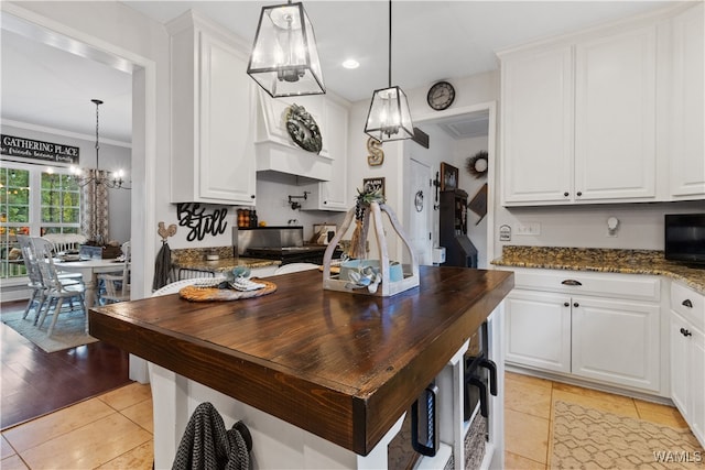 kitchen featuring light hardwood / wood-style flooring, white cabinetry, hanging light fixtures, and ornamental molding