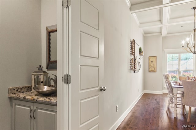 hallway featuring beam ceiling, sink, dark wood-type flooring, coffered ceiling, and a notable chandelier