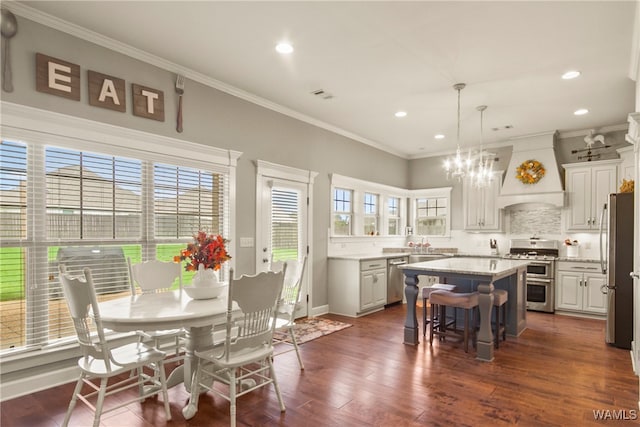 kitchen featuring appliances with stainless steel finishes, premium range hood, white cabinetry, dark hardwood / wood-style floors, and a kitchen island