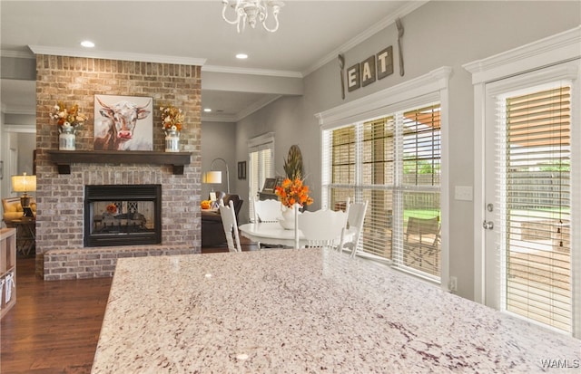 dining room featuring a notable chandelier, a fireplace, crown molding, and dark wood-type flooring