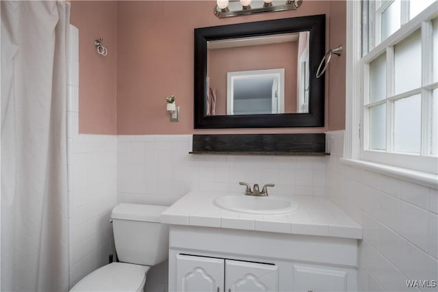 bathroom featuring vanity, tile walls, and toilet