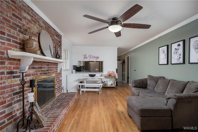 living room featuring ceiling fan, ornamental molding, light hardwood / wood-style floors, brick wall, and a brick fireplace