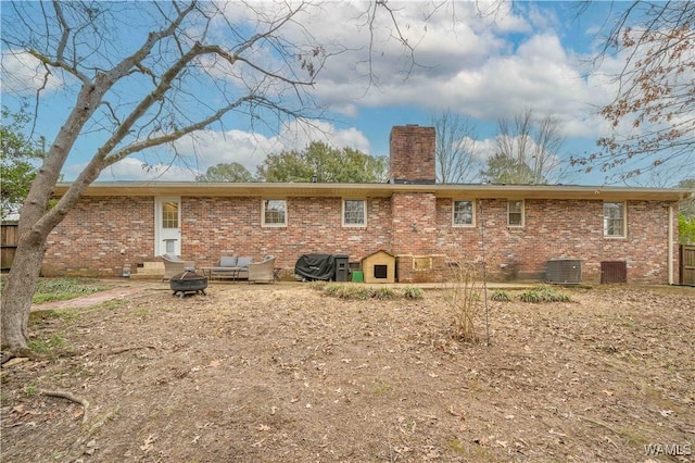 back of house with central AC unit and an outdoor fire pit