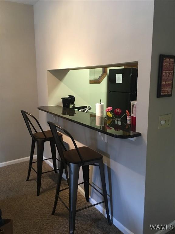 708 11th St Unit 226, Tuscaloosa, AL 35401 - kitchen featuring freestanding refrigerator, carpet floors, a breakfast bar area, and a desk