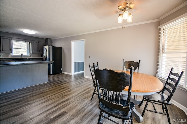 dining room with dark wood-type flooring, sink, ceiling fan, ornamental molding, and a textured ceiling