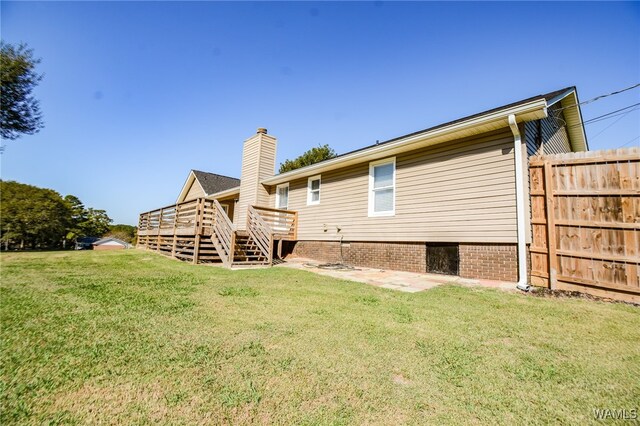 back of property featuring a wooden deck and a yard