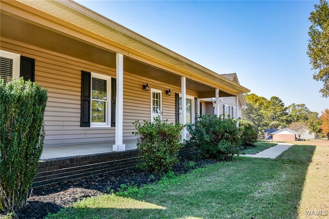 doorway to property featuring a porch and a yard