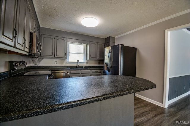 kitchen featuring sink, stainless steel appliances, dark hardwood / wood-style floors, kitchen peninsula, and a textured ceiling