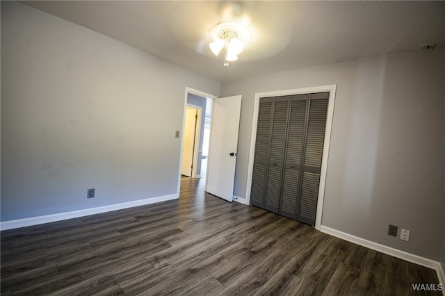 unfurnished bedroom featuring a textured ceiling, ceiling fan, dark wood-type flooring, and a closet